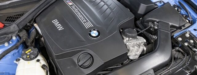 Ein BMW-Motor in einem blauen Auto mit M Performance-Logo und schwarzem Gehäuse