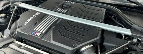 Der geöffnete Motorraum eines Autos mit sauberer schwarzen Motorabdeckung.